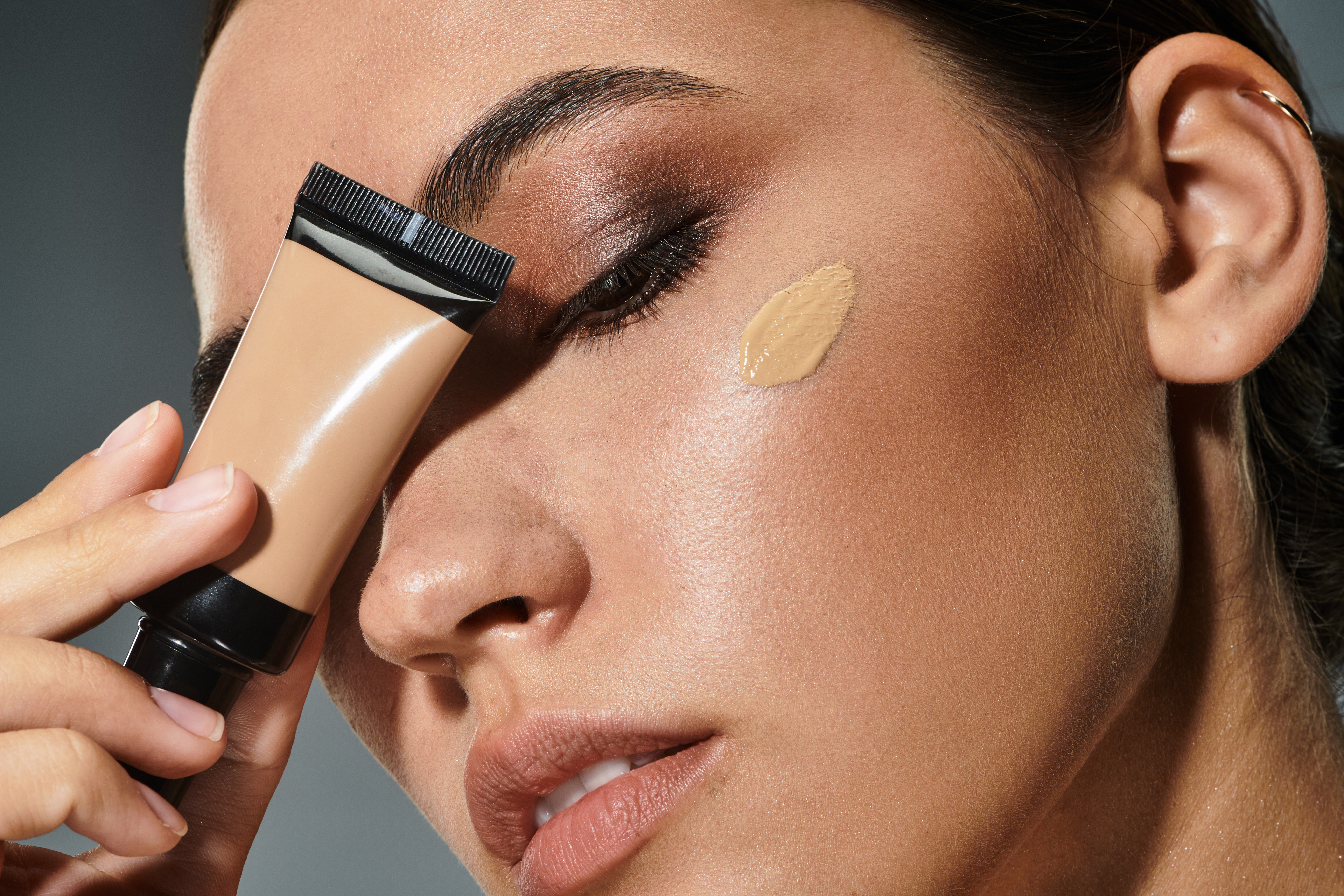 stylish-woman-applying-foundation-while-preparing-glamorous-evening-event-indoors